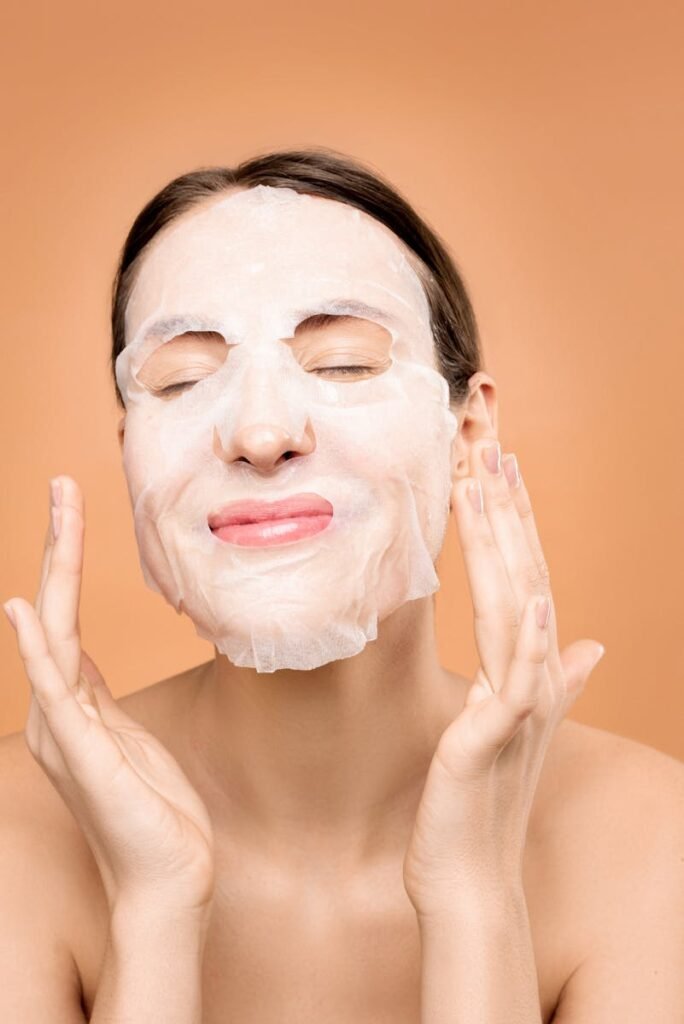 Skincare Madrid cuidado facial - Woman smiling with a sheet face mask, embracing a skincare self-care moment.